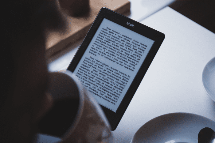 Close up of person drinking coffee while reading a kindle e-book