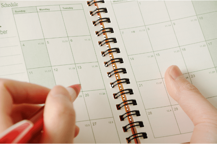 Close up of hand with pen hovering over a date book