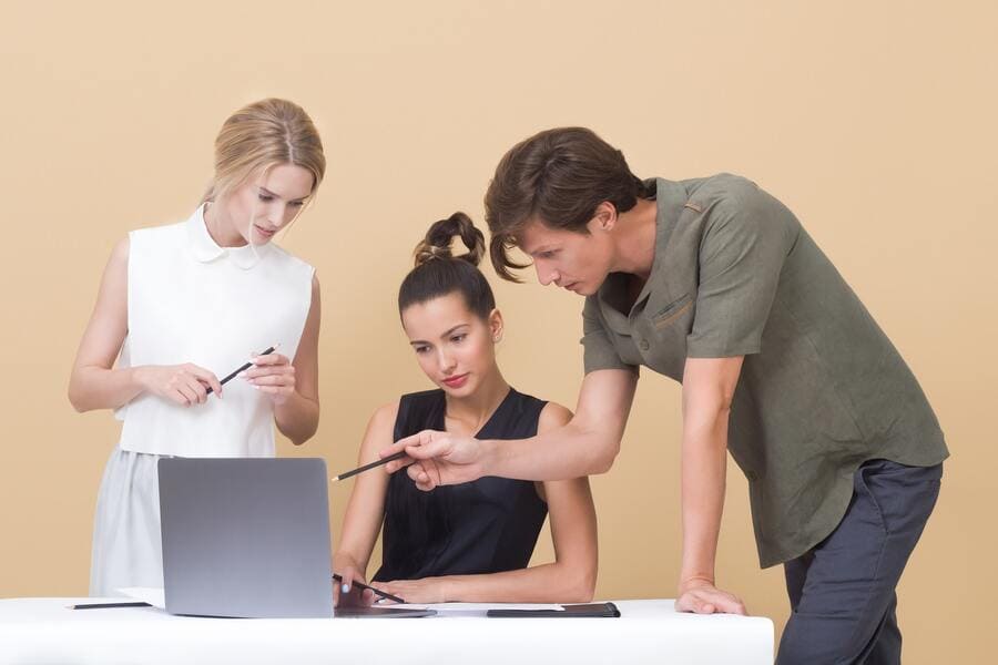 Coworkers giving each other feedback while looking at laptop