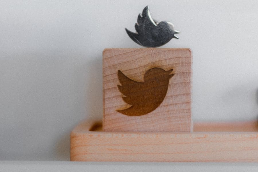 a silver twitter bird on top of a wooden block with the twitter logo burned on it