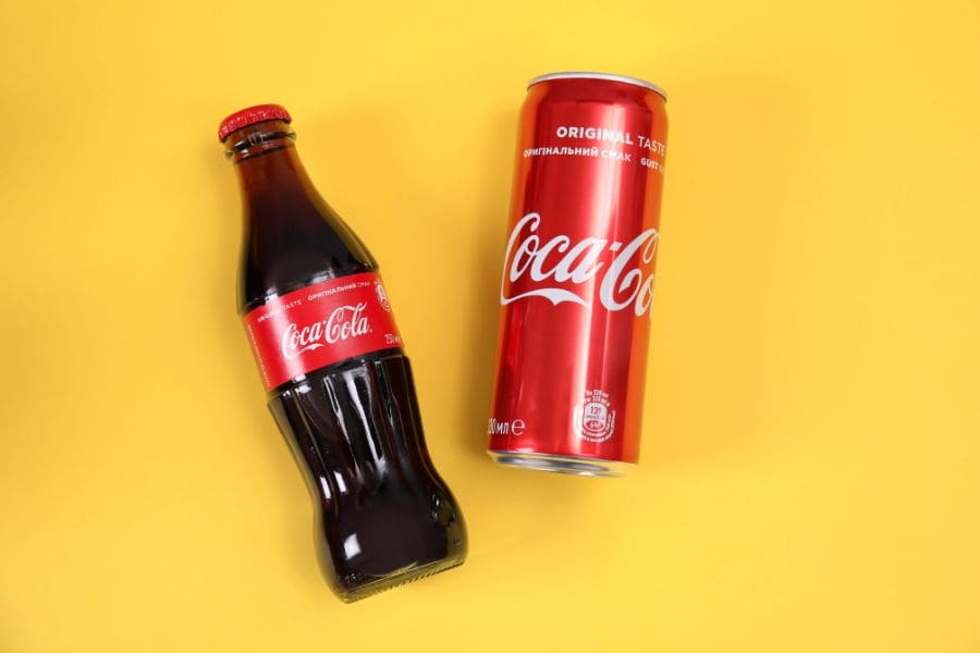 bottle and can of coca-cola on yellow background