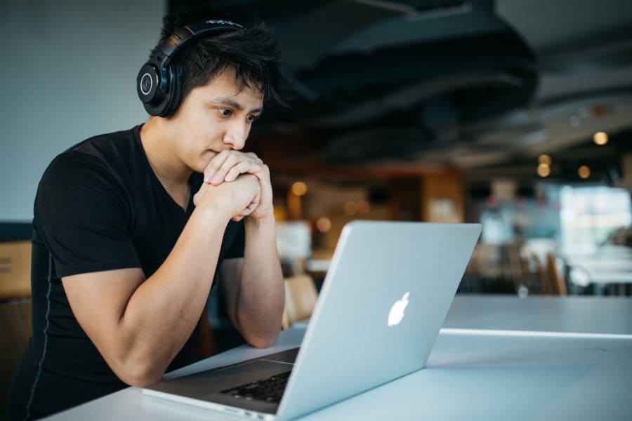 man with headphones staring at the laptop