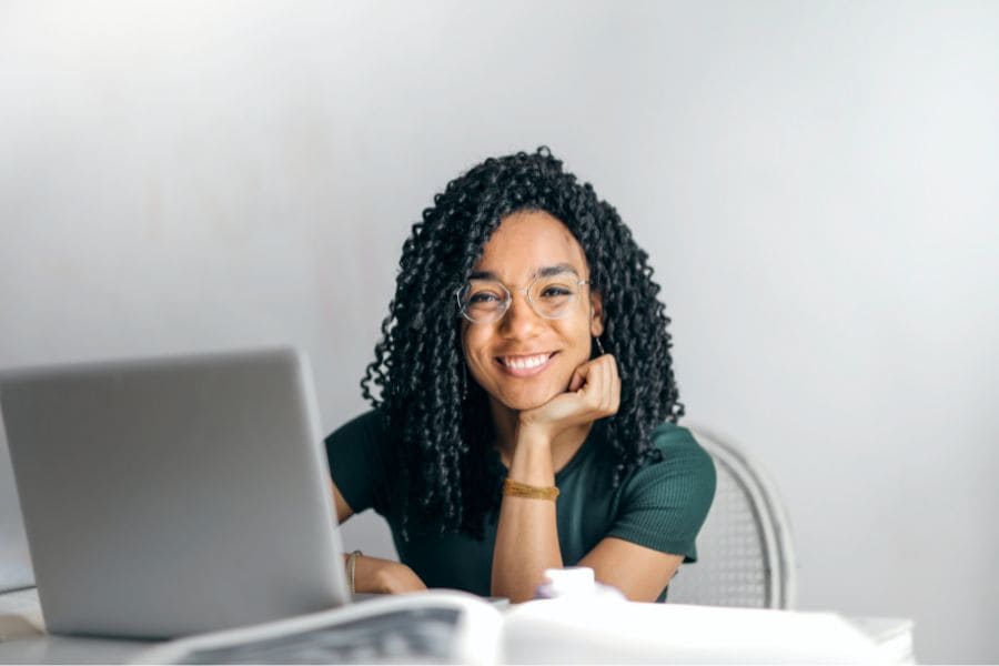 a woman seated before a laptop smiling 