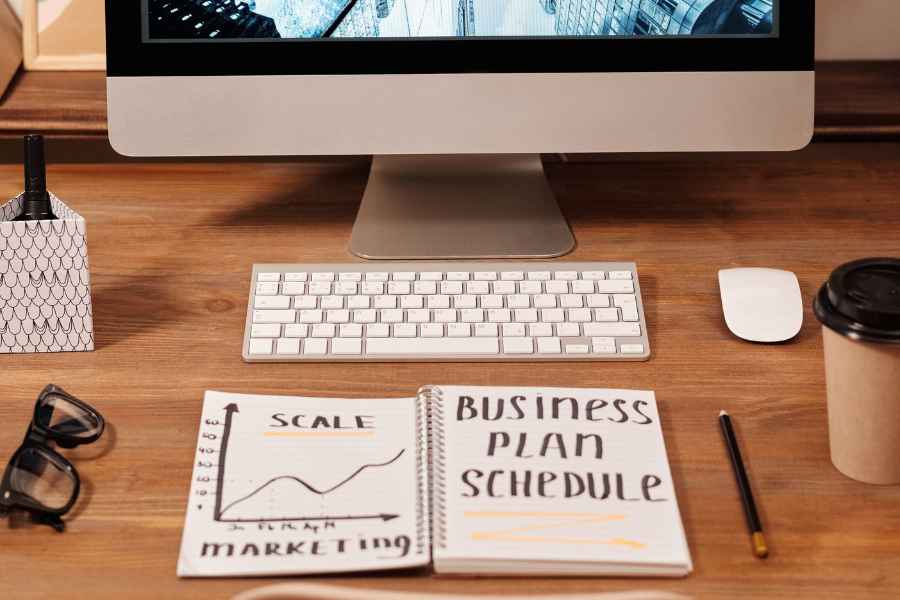 a notebook saying "business plan schedule" on a desk