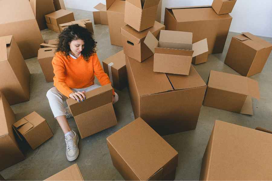 woman sitting among cardboard boxes