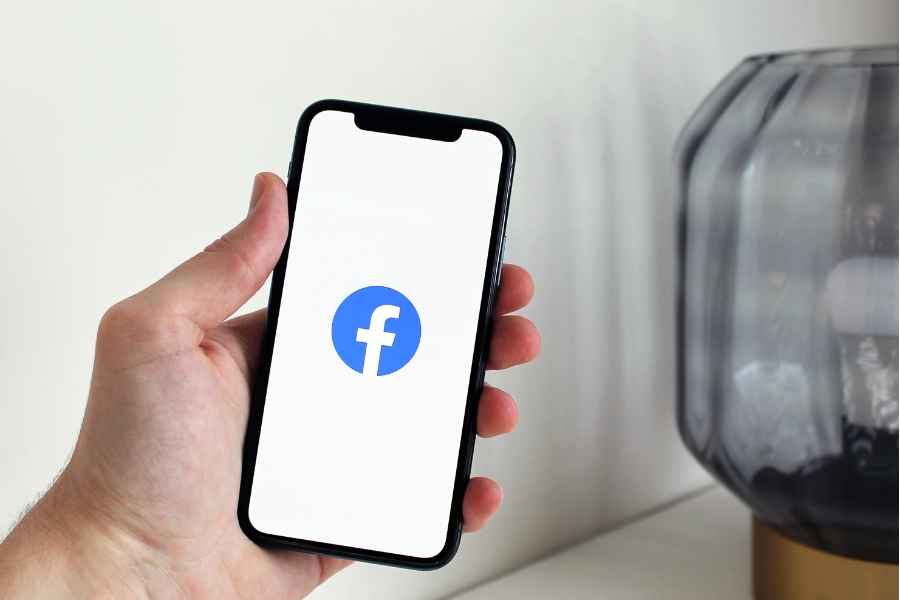 hand holding phone with facebook icon