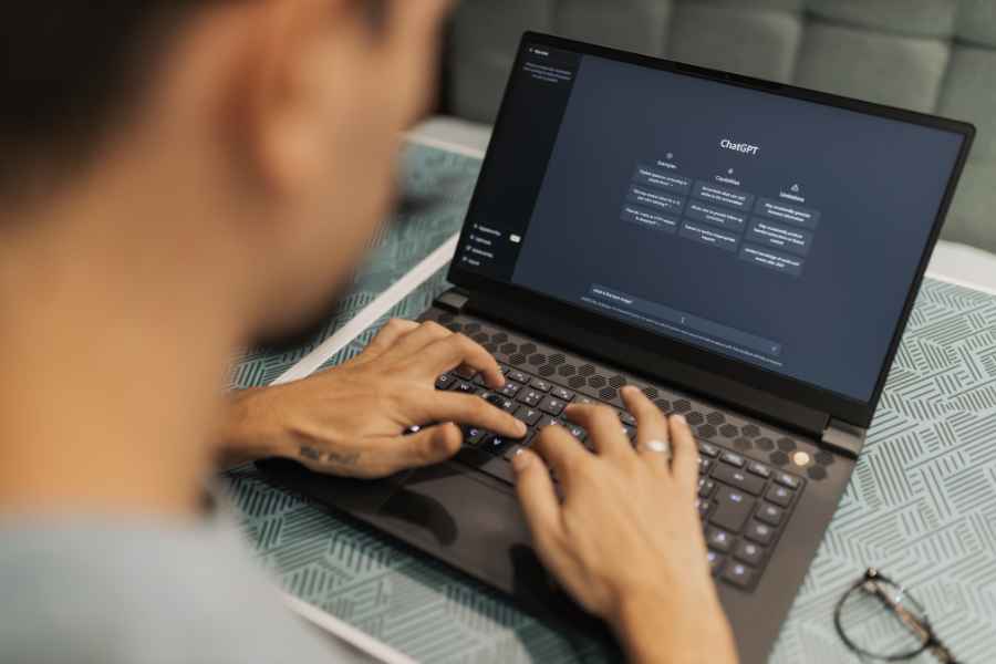 man typing on laptop which has ChatGPT on the screen