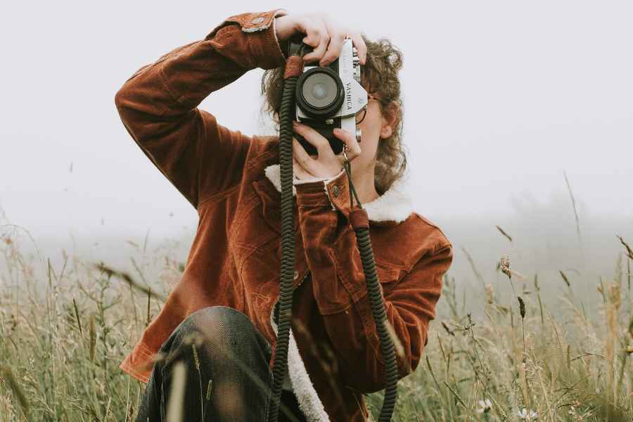 woman in a field holding camera 