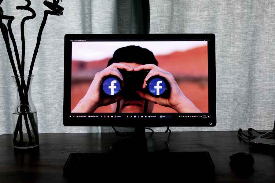 desktop with a man holding binoculars with the facebook icons