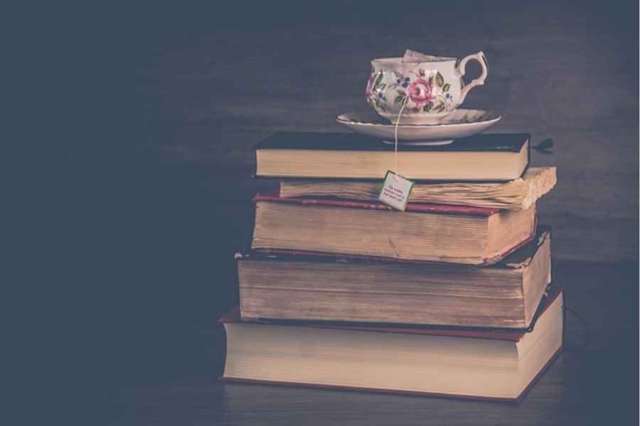 a stack of old books with a teacup on top