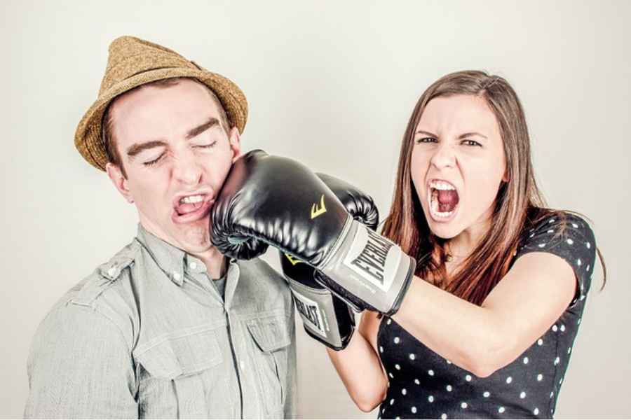 woman with boxing glove punching man with hat in the face