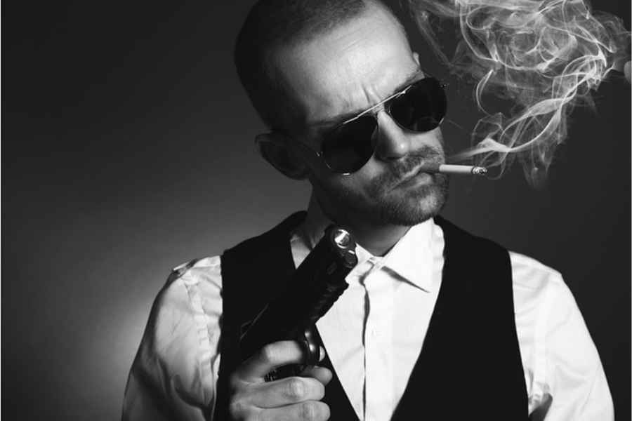 man with sunglasses holding gun and smoking