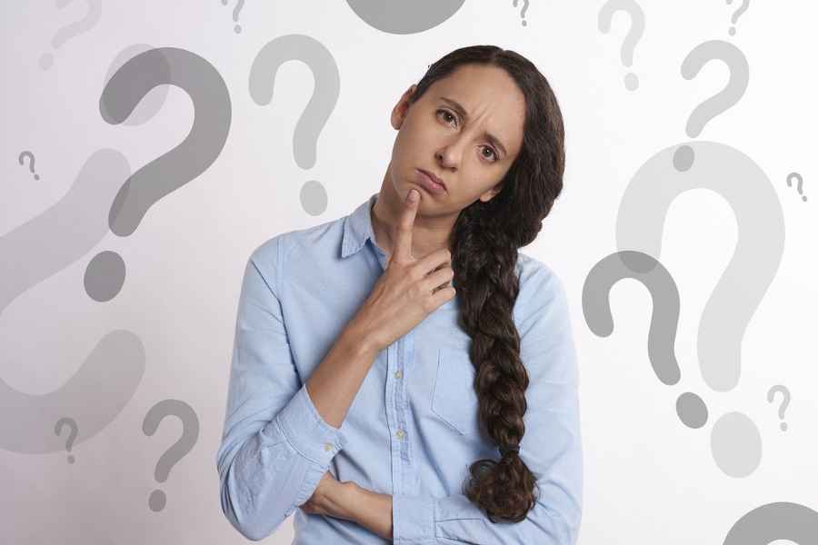 woman tilting head in question with question marks behind her