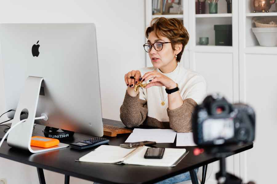 woman sitting in front of mac computer being filmed