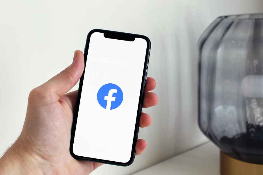 hand holding facebook logo on cell phone screen